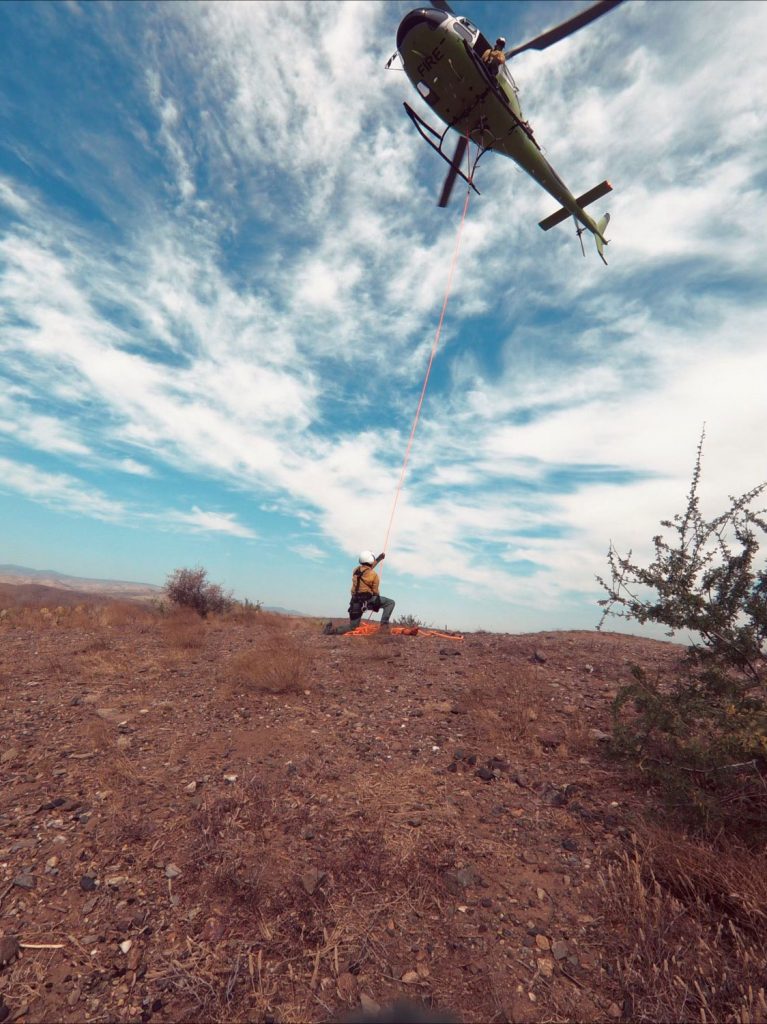 A helicopter hovering above a USFS worker