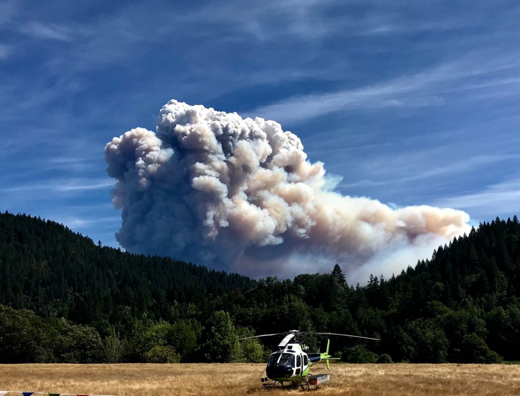 A helicopter in front of a cloud of smoke